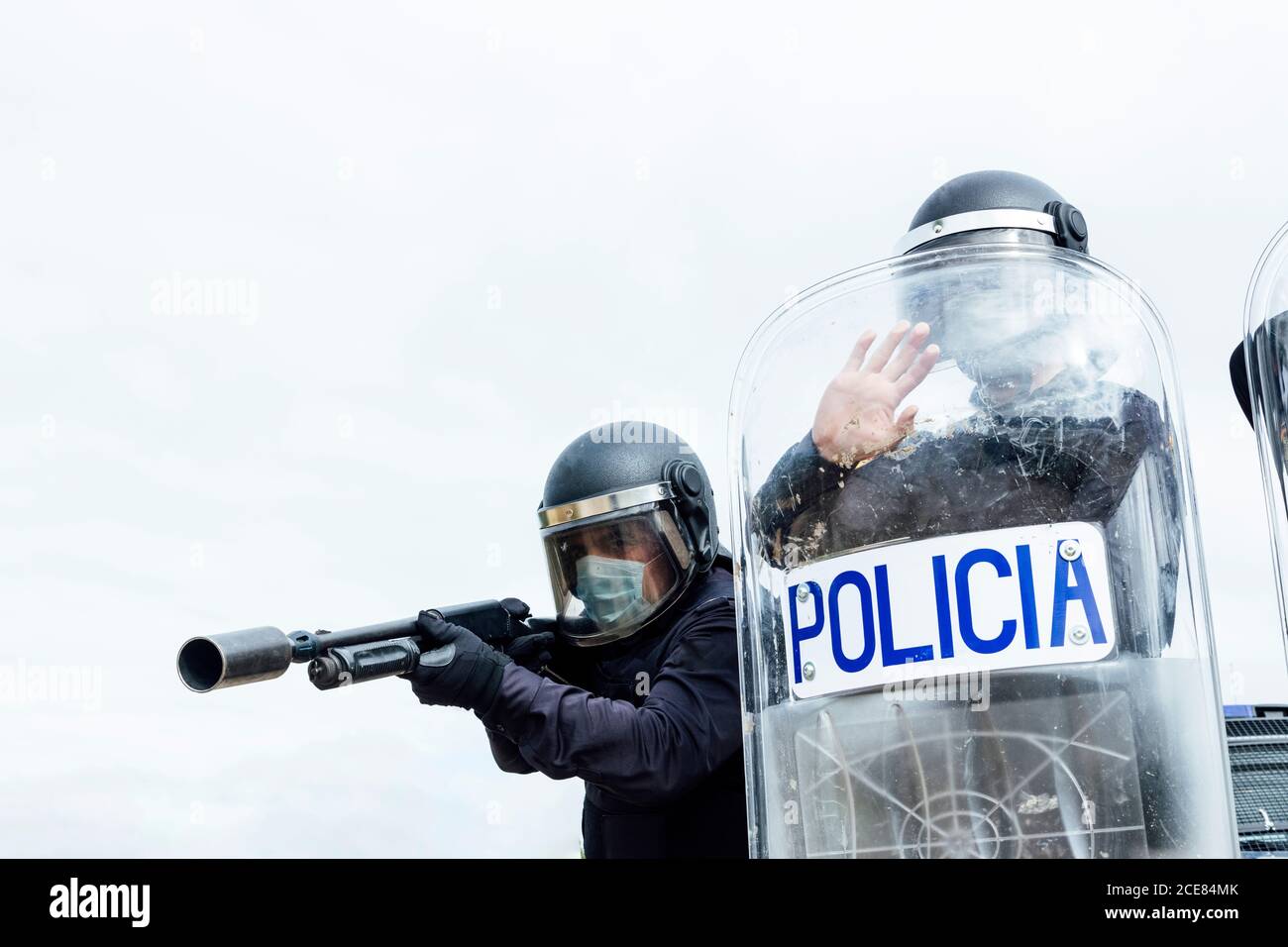 Faible angle de swat soldats dans les uniformes de protection et médical masques armés de fusil d'assaut et de bouclier anti-émeute et prêts pour le combat Banque D'Images