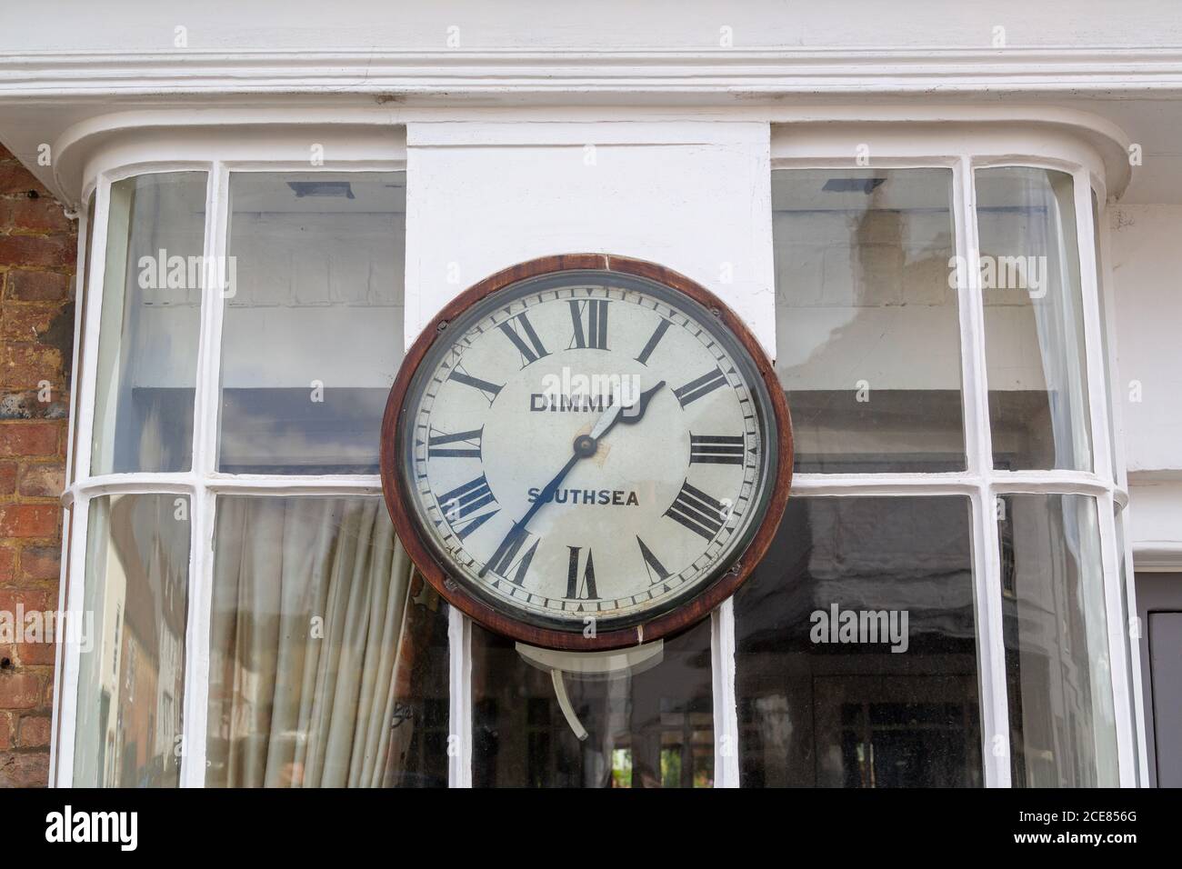 Une vieille horloge en bois à l'extérieur d'une baie vitrée dans une rue haute, Hambledon, Hampshire Banque D'Images