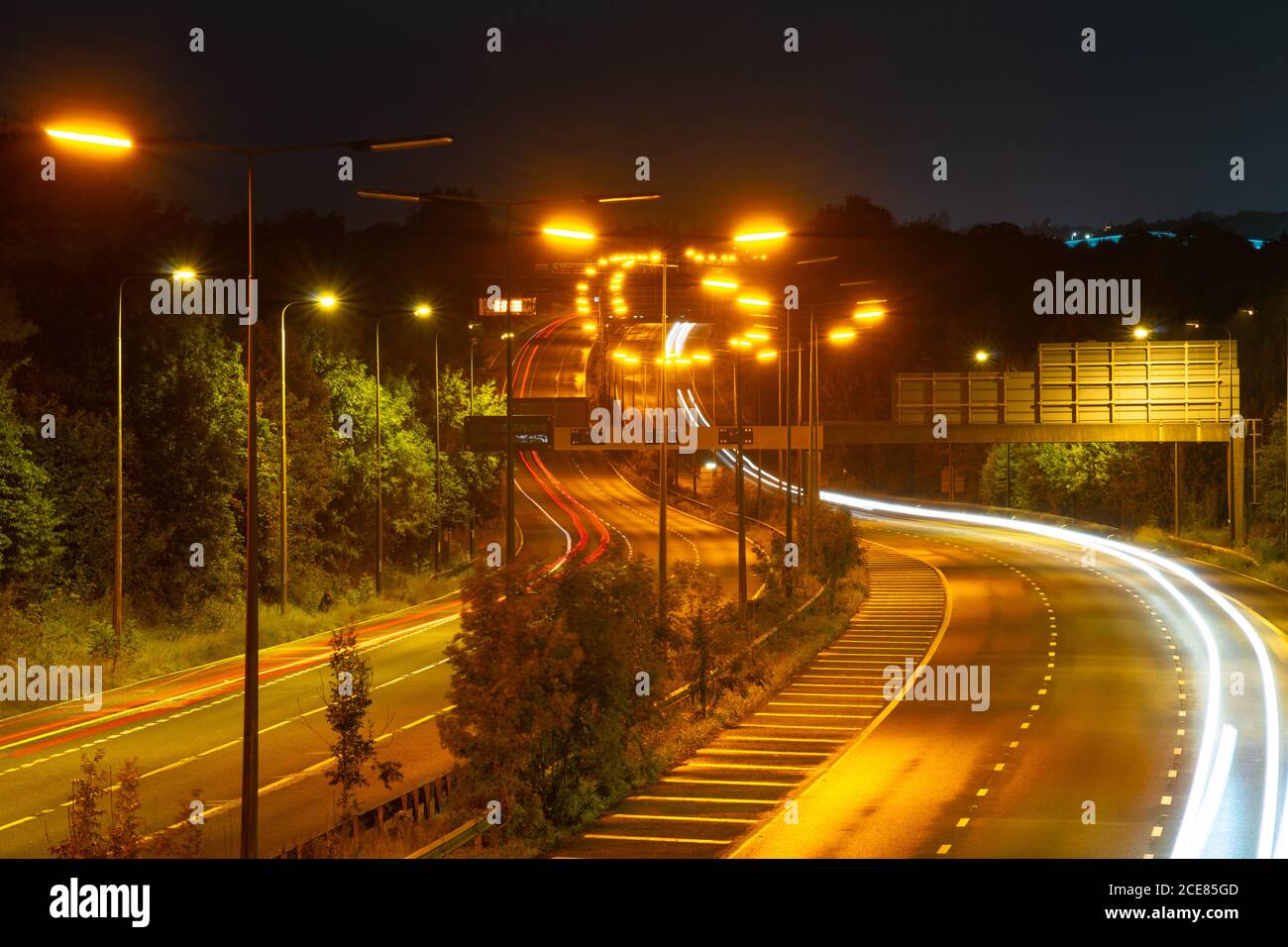 Autoroute M60 entre Brinnington et Bredbury en regardant vers le nord la nuit, sentiers de lumière, avec sortie 25 derrière. Circulation nocturne, route, Angleterre, Royaume-Uni Banque D'Images