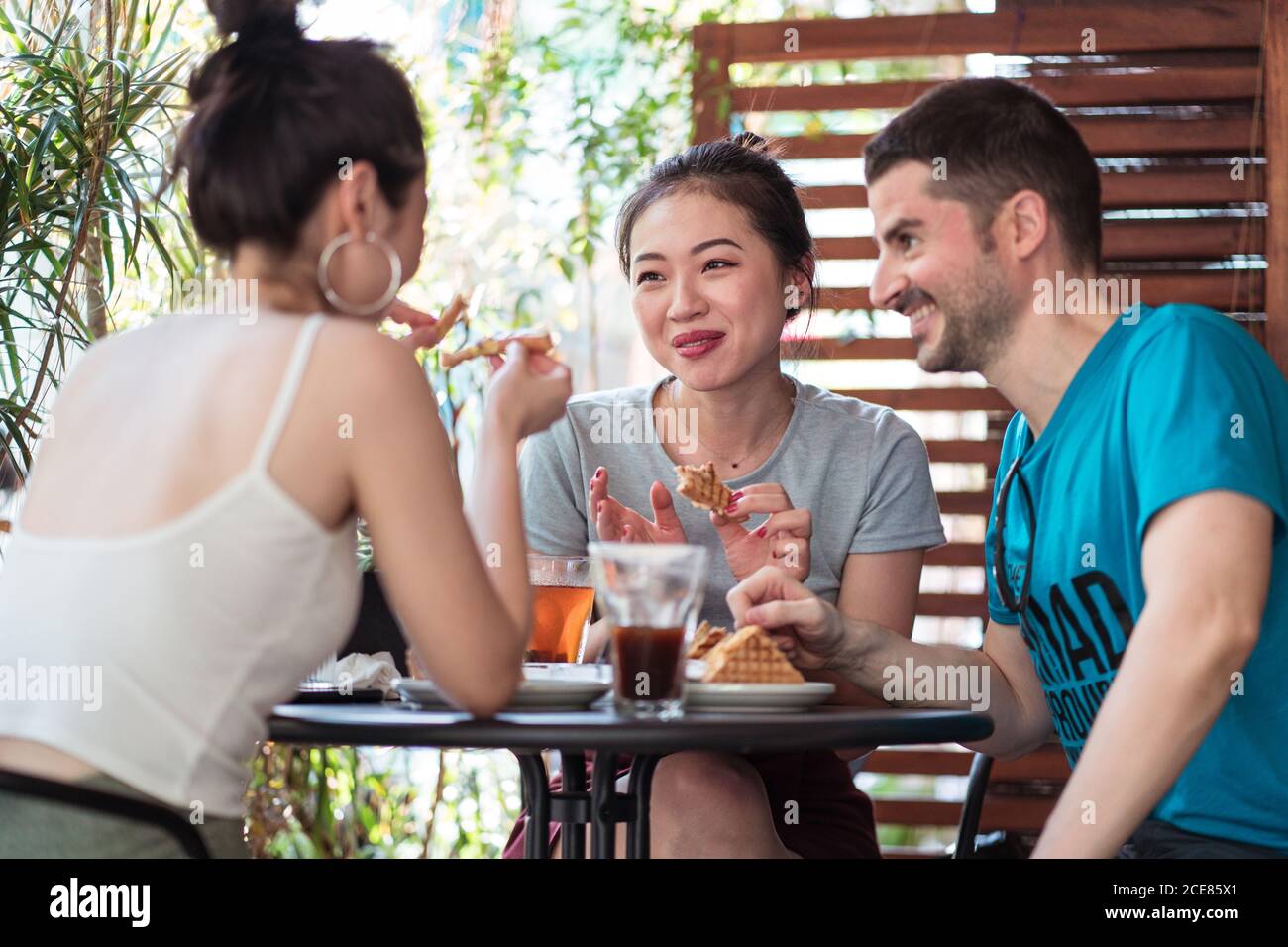 Des amis multiethniques gais déjeunent au café Banque D'Images