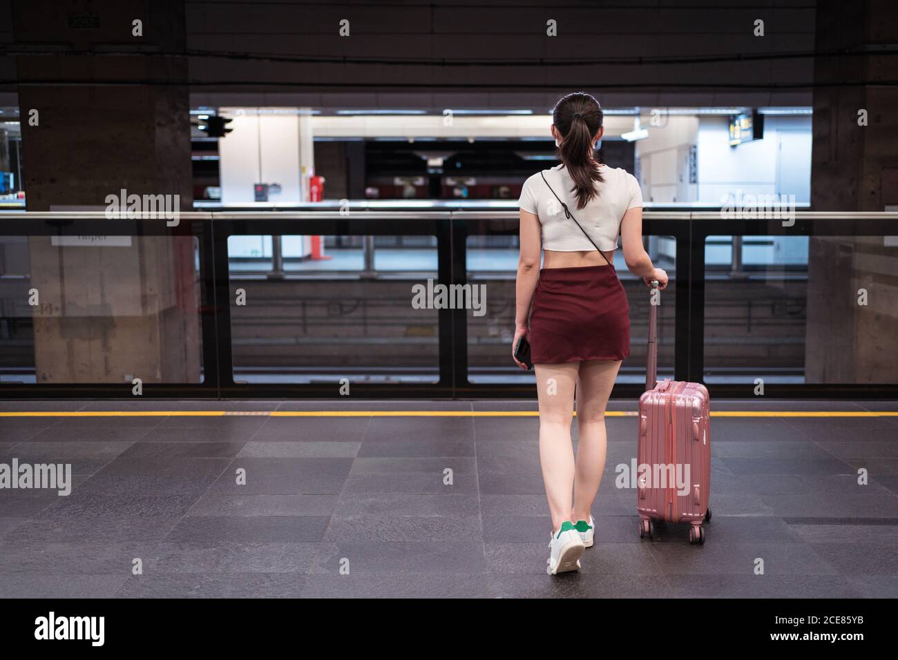 Vue arrière de la jeune femme méconnue en petite jupe de marche avec valise  à la gare en attendant le train Photo Stock - Alamy