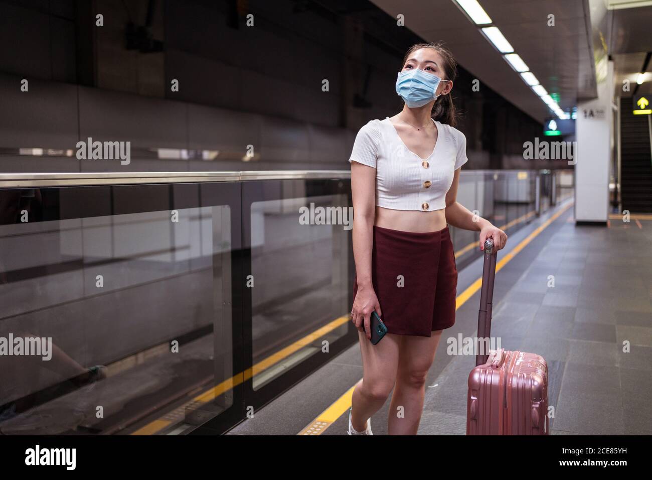 Pleine longueur jeune femme asiatique en mini jupe debout avec valise à la  gare en attendant le train Photo Stock - Alamy