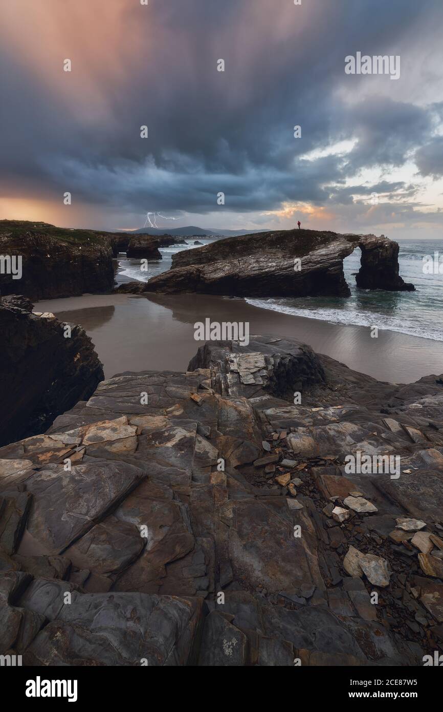 Rochers rugueux sur le rivage d'un océan calme sous des nuages gris dans un ciel lumineux Banque D'Images