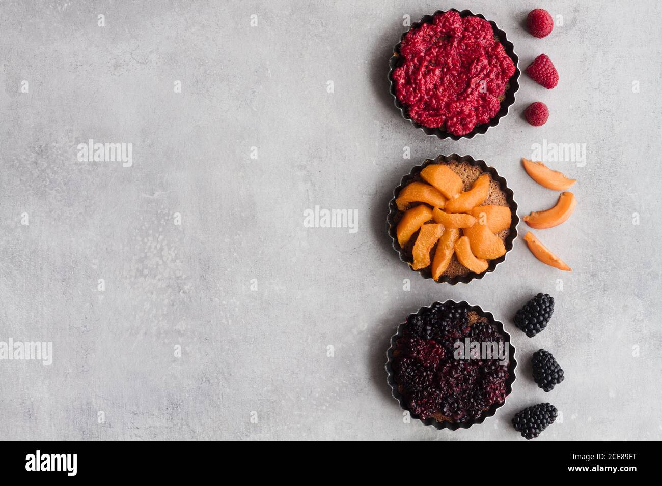 Vue de dessus des tartes avec divers fruits mûrs et baies disposées en ligne sur la table Banque D'Images