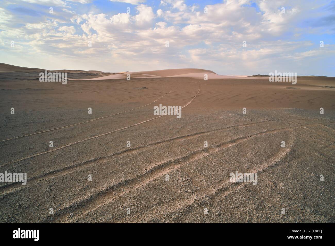 Vue spectaculaire sur le désert avec des collines de sable et des traces surface sèche avec texture ample sous ciel serein avec basse nuages en lumière du jour Banque D'Images