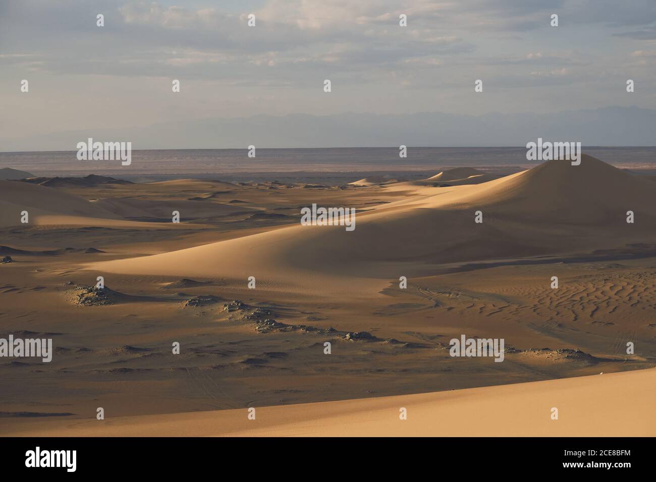 Vue sur le paysage du désert avec des dunes de sable et des pierres sans forme avec une surface en rade sous un ciel pittoresque avec des nuages l'après-midi Banque D'Images