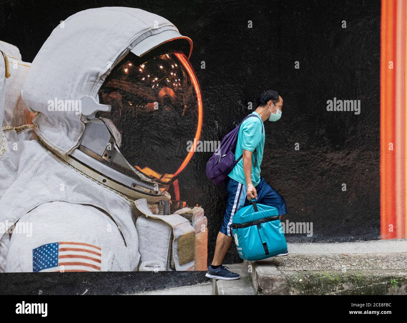 Hong Kong. 31 août 2020. HONG KONG, HONG KONG SAR : 31 AOÛT 2020. Un travailleur de Deliveroo portant un masque passe devant l'image d'un astronaute portant son masque à Hong Kong. Bien que le port de masques à l'extérieur ait été un peu détendu, tout le monde dans la rue porte toujours un. L'art de rue annonce l'artiste français Vincent FournierÕs exposition, Space Project à la galerie la Galerie à Aberdeen Street Hong Kong. Alamy Live News/Jayne Russell Credit: Jayne Russell/Alamy Live News Banque D'Images