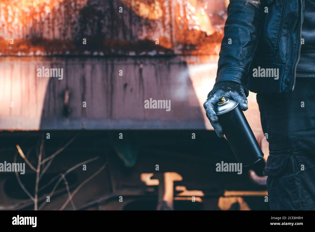Sans-abri pistolage vieux train wagon avec aérosol. Méconnaissable personne mâle part close up en image conceptuelle avec focus sélectif. Banque D'Images