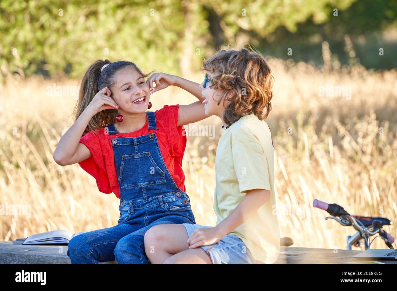Un garçon et une fille de dix ans se grignoter sur une table en bois dans la campagne, avec des fruits, des sandwiches et de l'eau. Banque D'Images