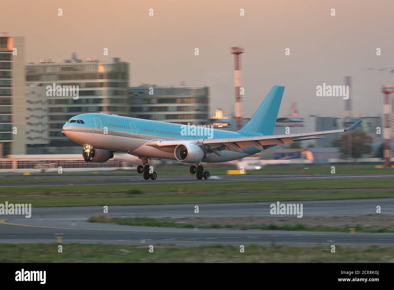 Atterrissage d'un avion de passagers à carrosserie large bleu avec toucher de la piste à l'aéroport au coucher du soleil Banque D'Images