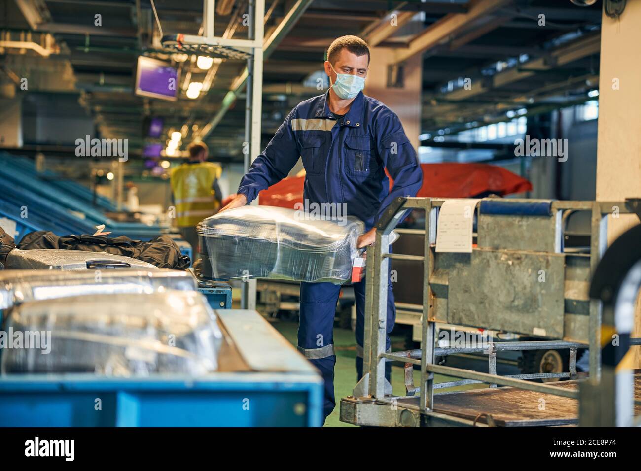 Homme dans un ensemble mettant une valise sur un chariot Banque D'Images