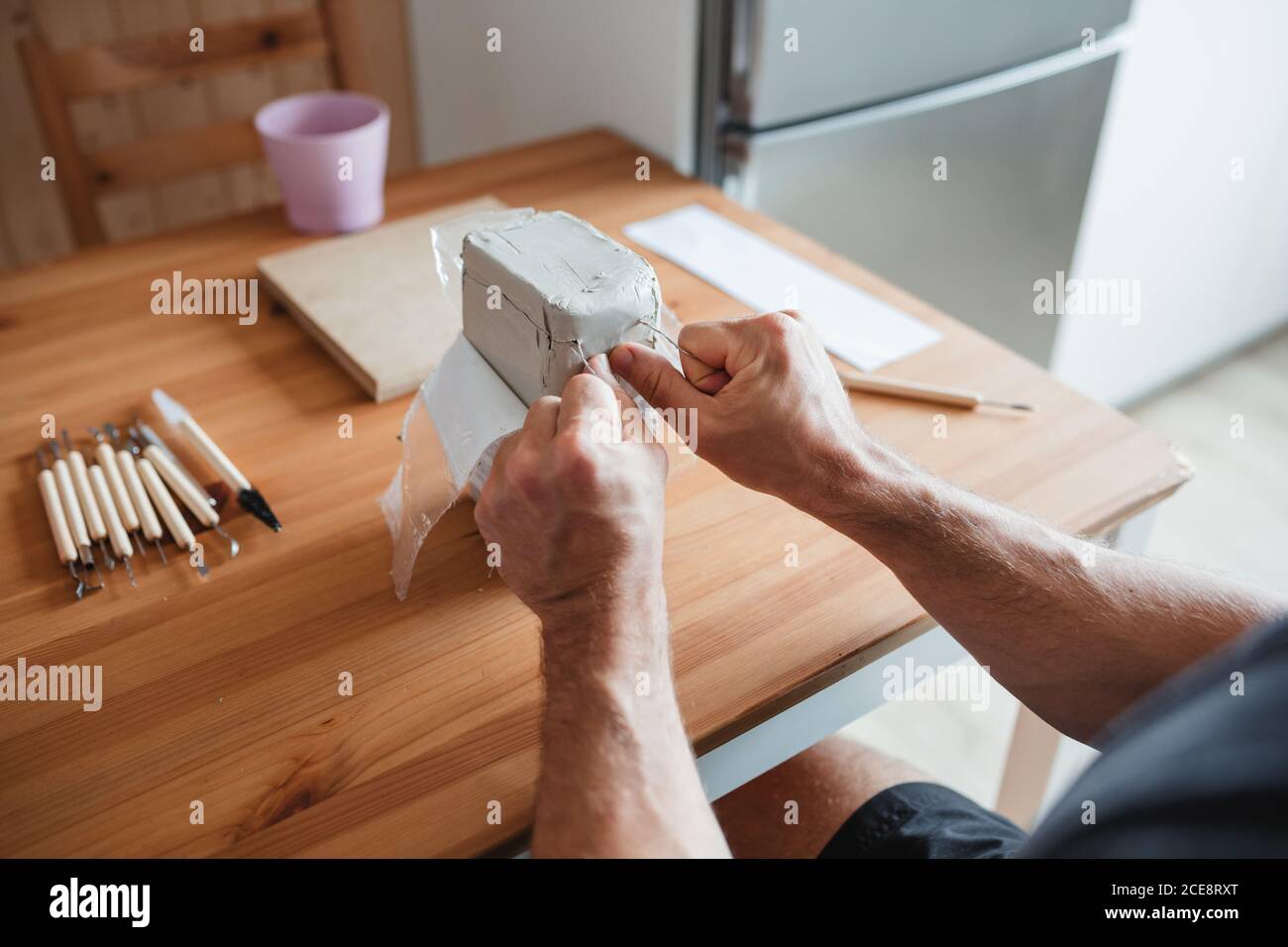 ceramiste mâle méconnaissable assis à la table et préparant l'argile pour création de poteries Banque D'Images