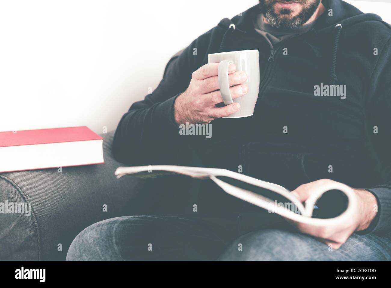 gros plan du magazine ou du journal caucasien sur un canapé tout en tenant une tasse de café Banque D'Images