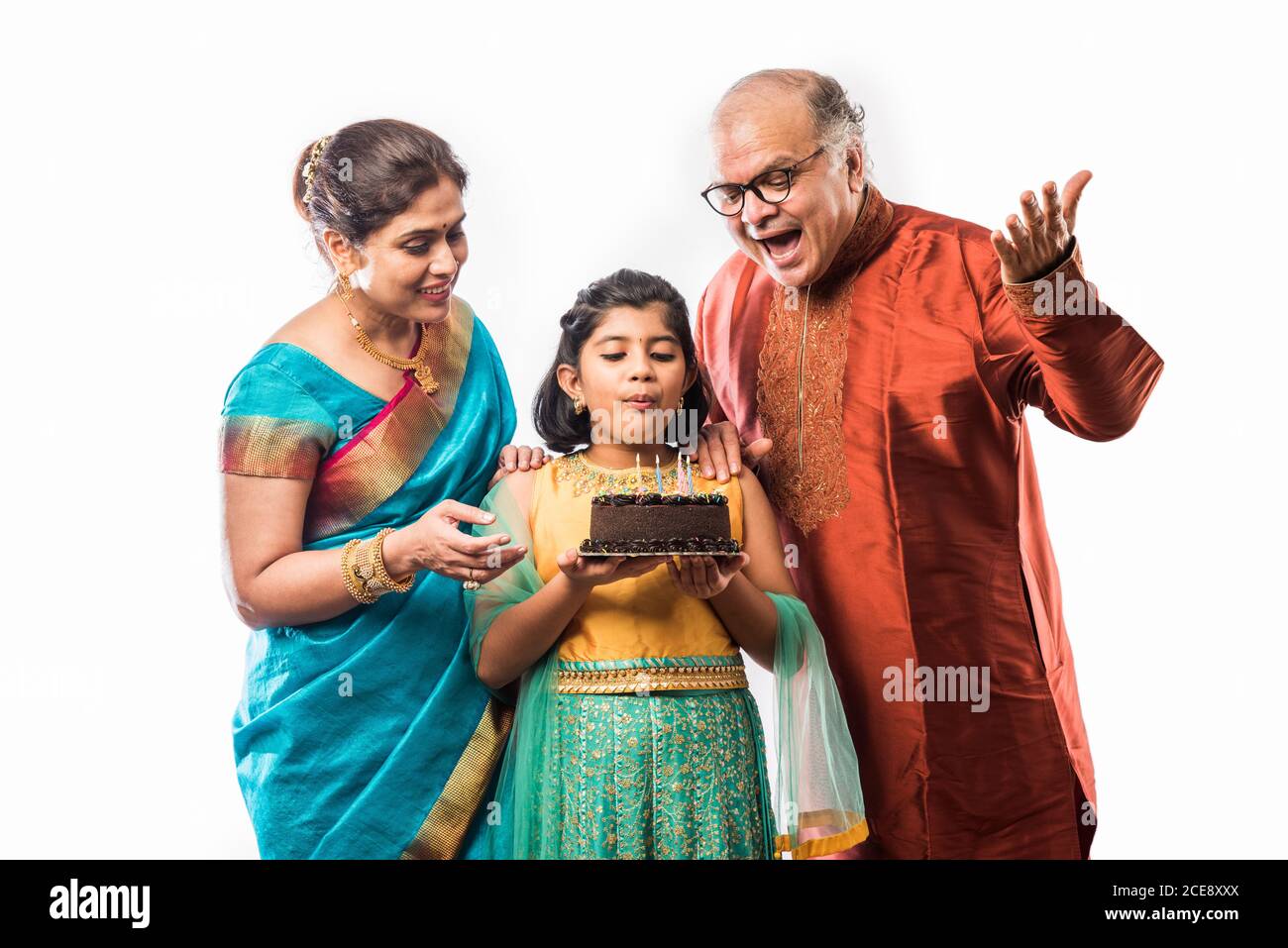 Petite petite fille asiatique ou petite fille qui fête son anniversaire avec les grands-parents tout en portant des vêtements ethniques Banque D'Images