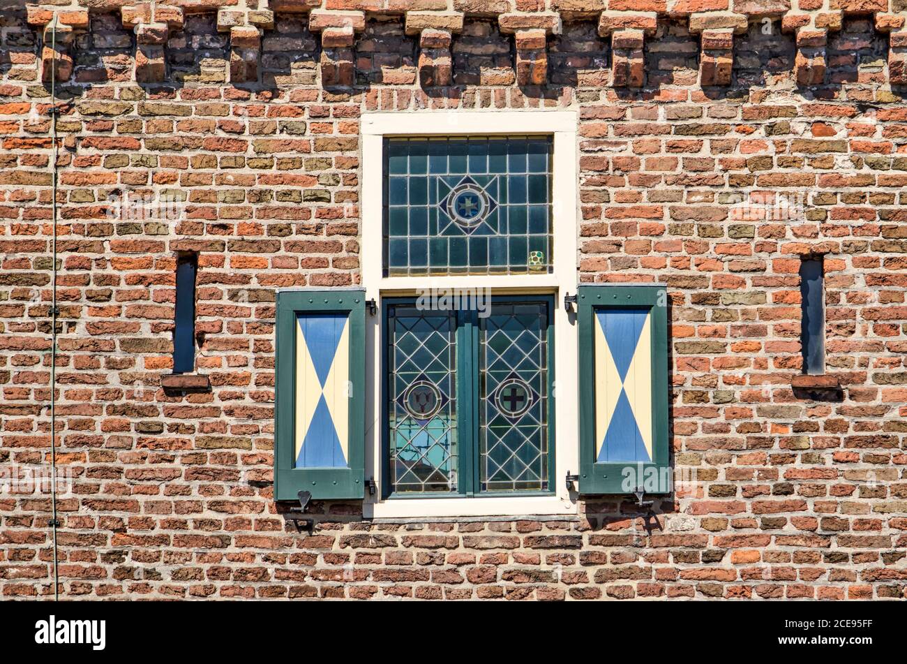 Hattem, pays-Bas, 31 juillet 2020 : partie de la façade du Dijkpoort (digue), avec une petite fenêtre en vitraux avec volets en bois dans un b Banque D'Images