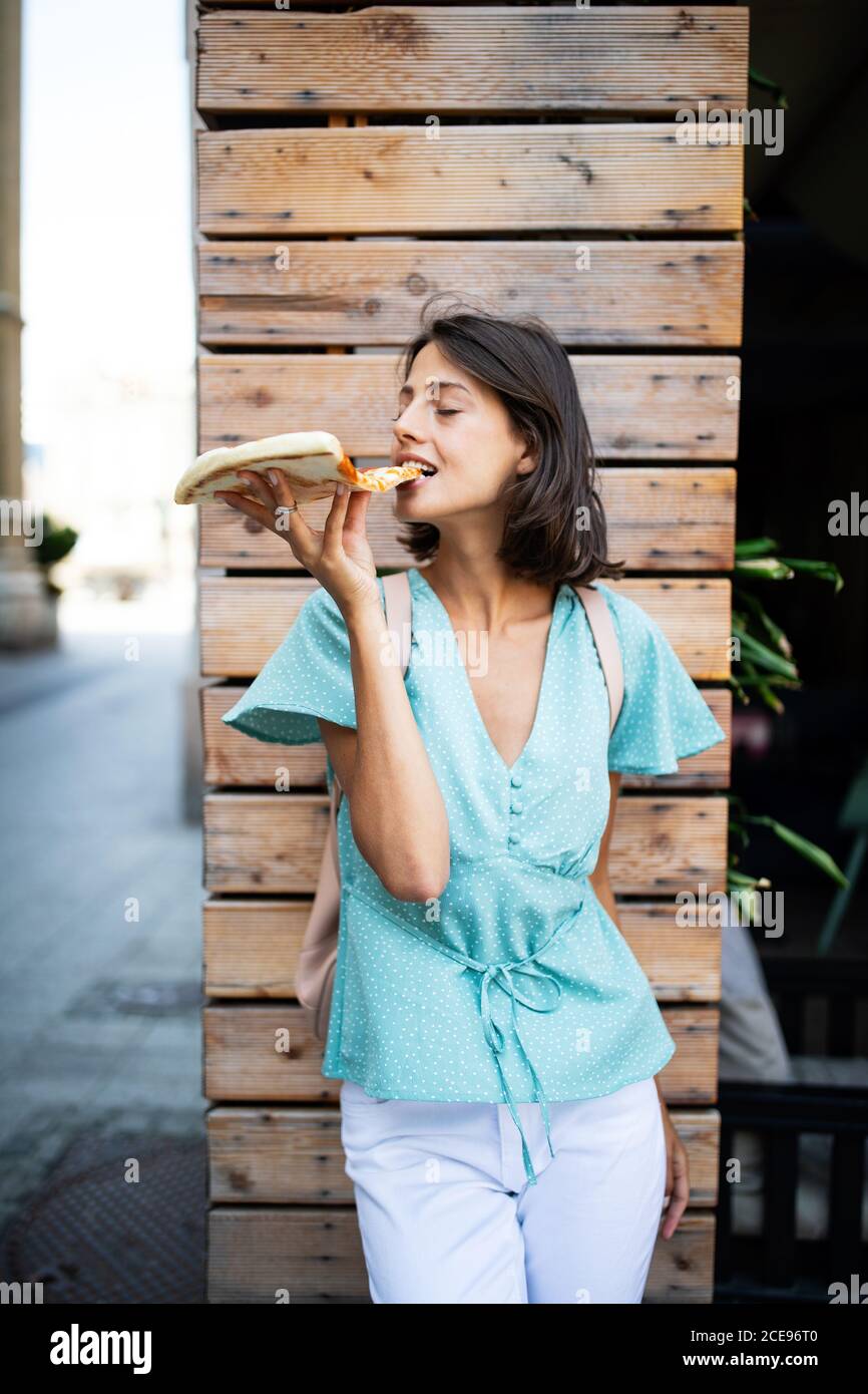 Belle jeune femme mangeant une tranche de pizza à l'extérieur Banque D'Images