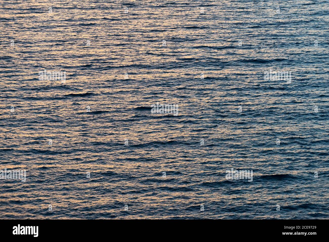 La mer au coucher du soleil dans un vent peu profond avec un petit surface ondulée, lumière du soir orange et bleue Banque D'Images