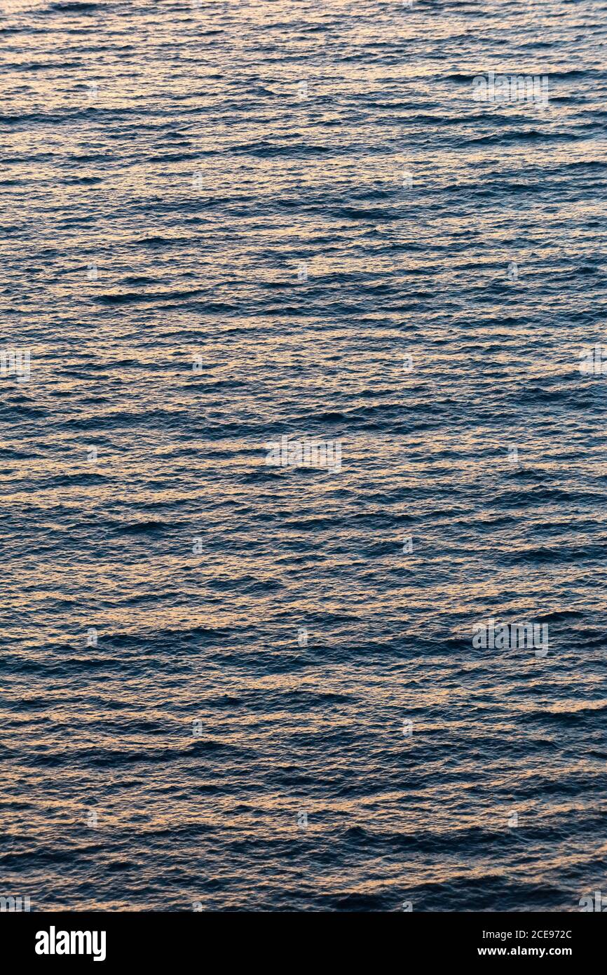 La mer au coucher du soleil dans un vent peu profond avec un petit surface ondulée, lumière du soir orange et bleue Banque D'Images