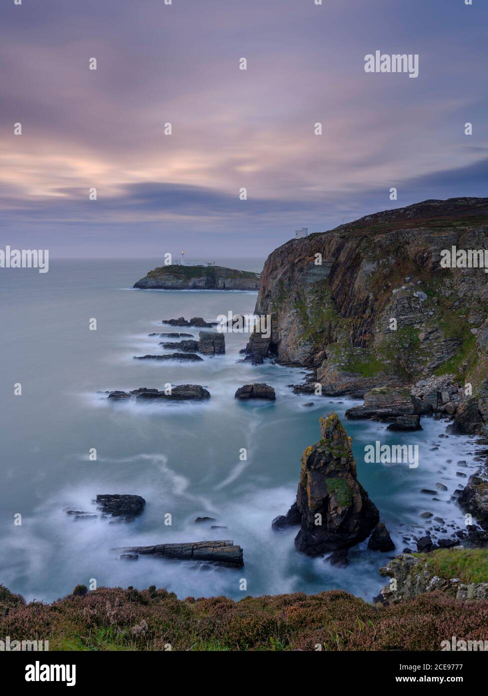 Vue sur le coucher du soleil vers le phare de South Stack sur Anglesey. Banque D'Images