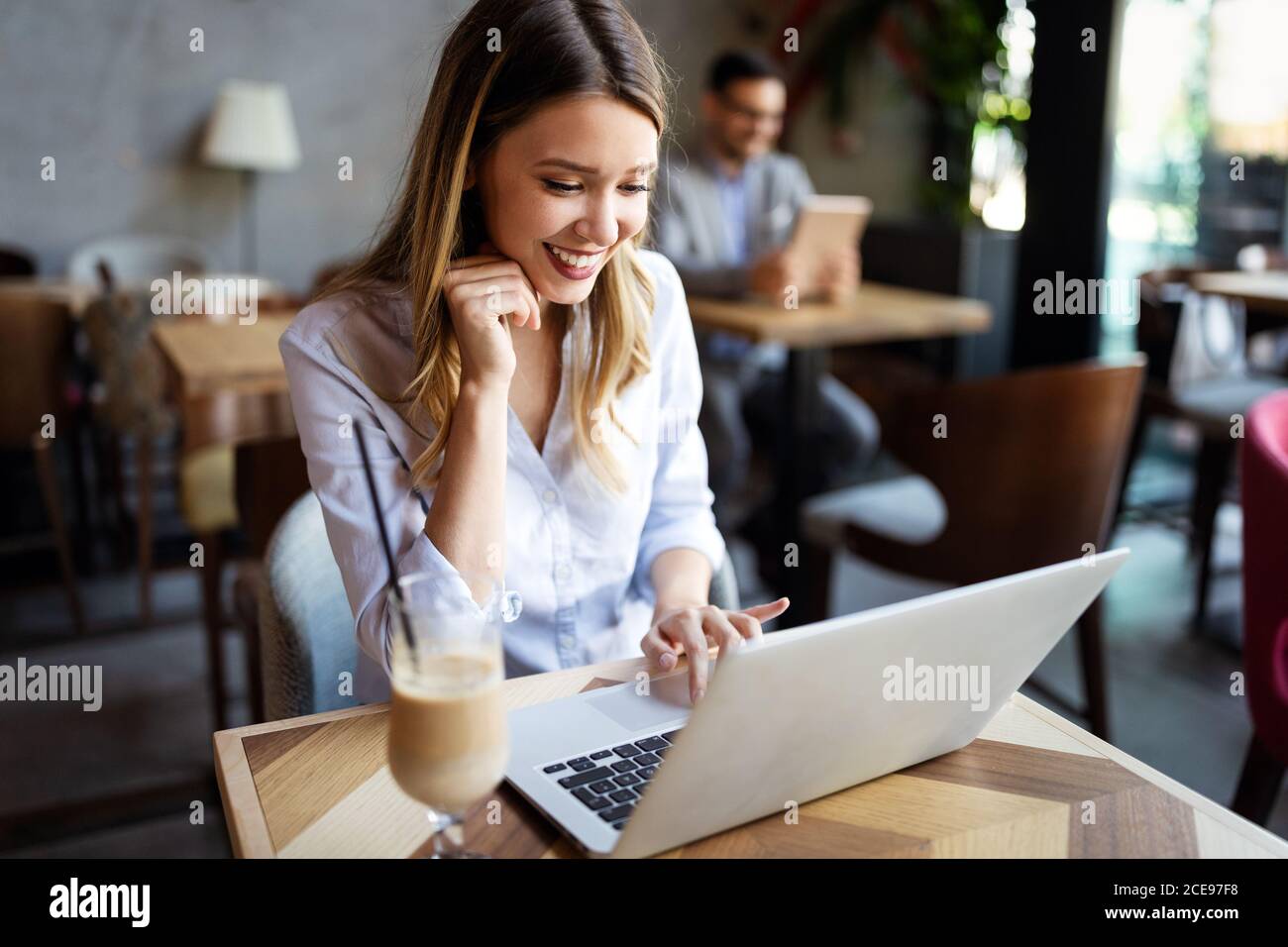 Portrait d'une jeune belle businesswomen bénéficiant du café pendant le travail sur ordinateur portable, Banque D'Images