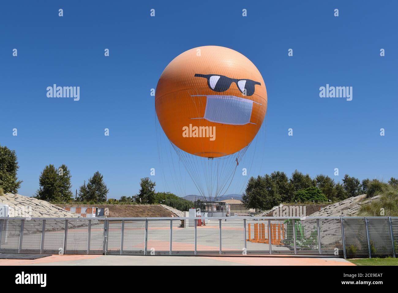 IRVINE, CALIFORNIE - 30 AOÛT 2020: Le Orange County Great Park Balloon Ride sport un masque COVID-19 et des lunettes de soleil comme il est assis à la gare. Banque D'Images