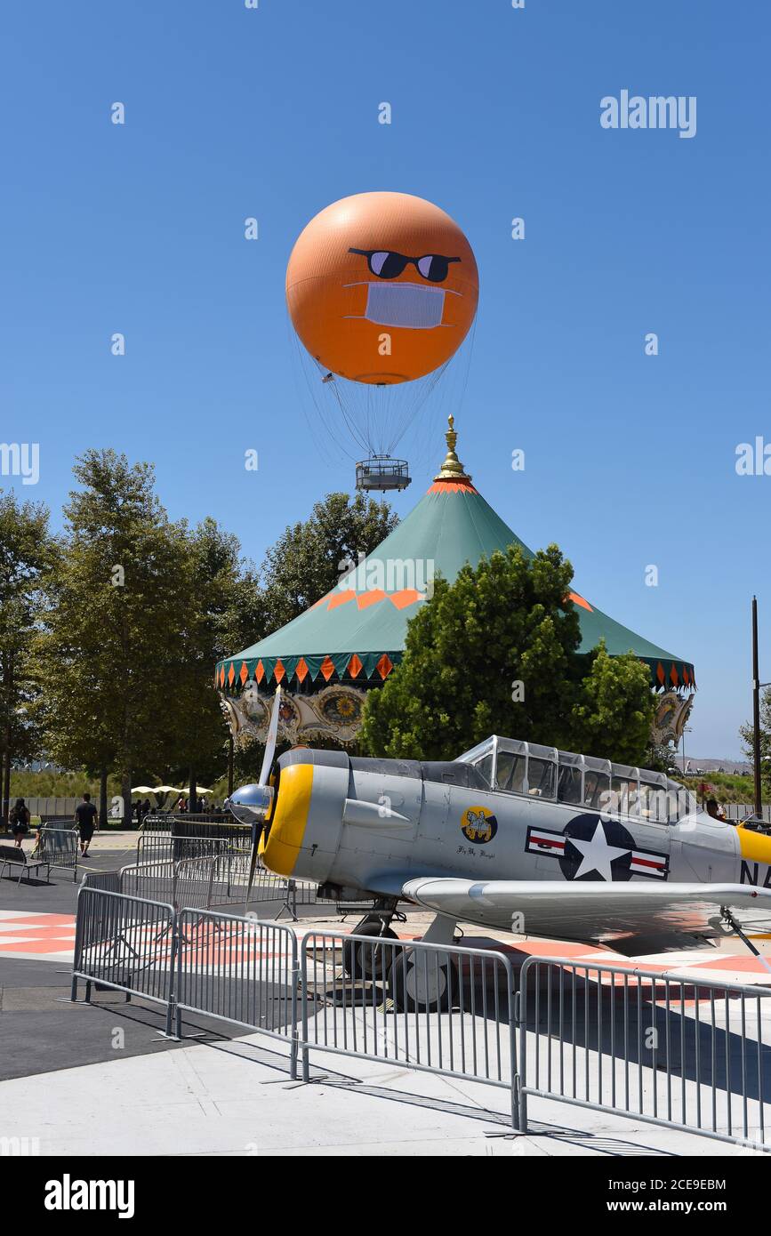 IRVINE, CALIFORNIE - 30 AOÛT 2020 : le grand parc d'Orange County en montgolfière avec masque et lunettes de soleil COVID-19 s'élève au-dessus du carrousel et pl Banque D'Images