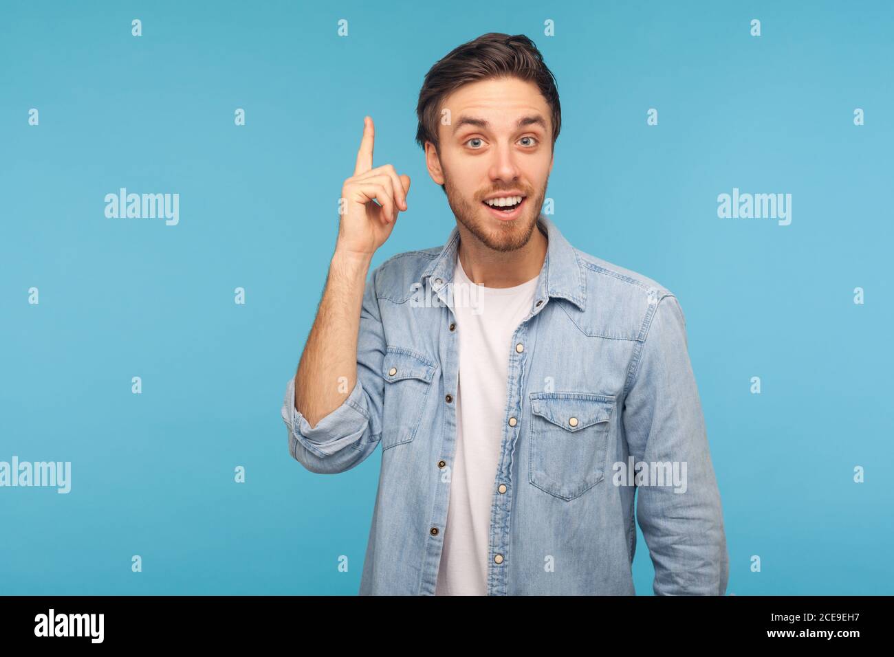 Portrait d'un homme heureux inspiré dans une chemise en denim ouvrier levant le doigt et ayant une idée de génie, l'aspect stupéfié par une solution intelligente soudaine, pensée créative. Banque D'Images