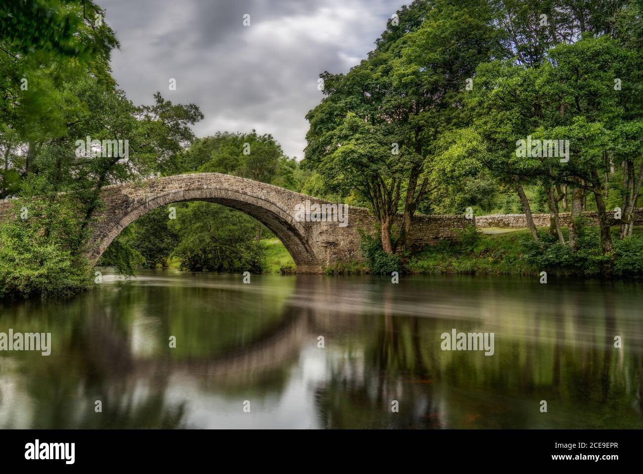 Pont Ivelet à Swaledale, dans le Yorkshire Dales, Angleterre. Rivière reflétant le pont à cheval avec arbres verts surplombant. Banque D'Images