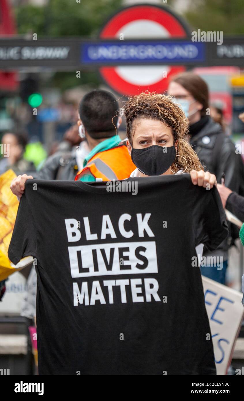 Une femme portant un masque facial tient un T-shirt noir Lives Matter pendant la marche de millions de personnes de Notting Hill à Hyde Park. Banque D'Images