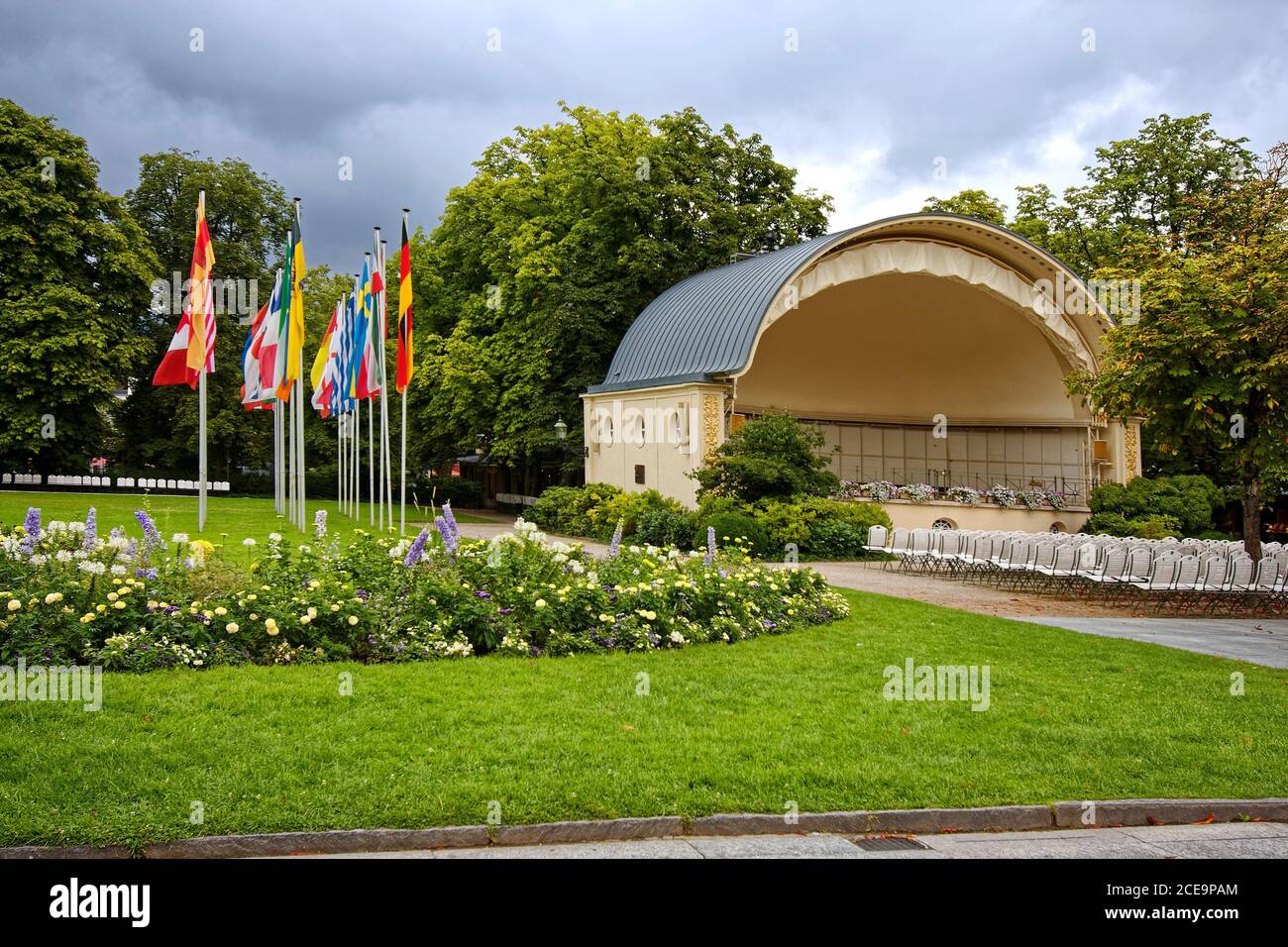 Salle de concert en plein air; spectacle en plein air; coquillages, sièges, rangée de grands drapeaux des nations; poteaux; coloré; herbe verte, arbres, Cultural Mile, Europe; B Banque D'Images