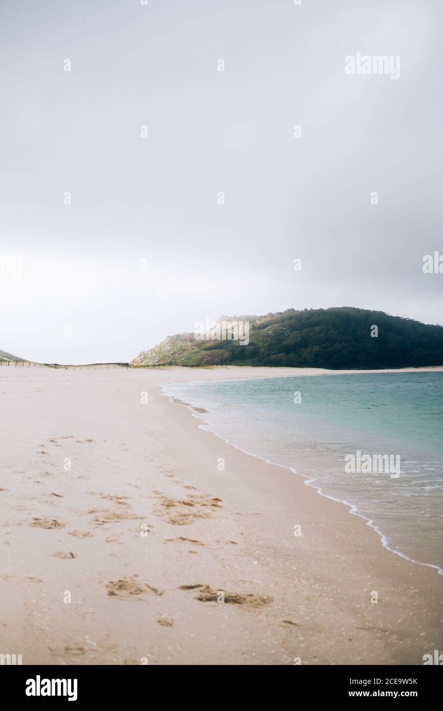 Vue verticale sur la plage de sable vide et la colline verdoyante. Banque D'Images