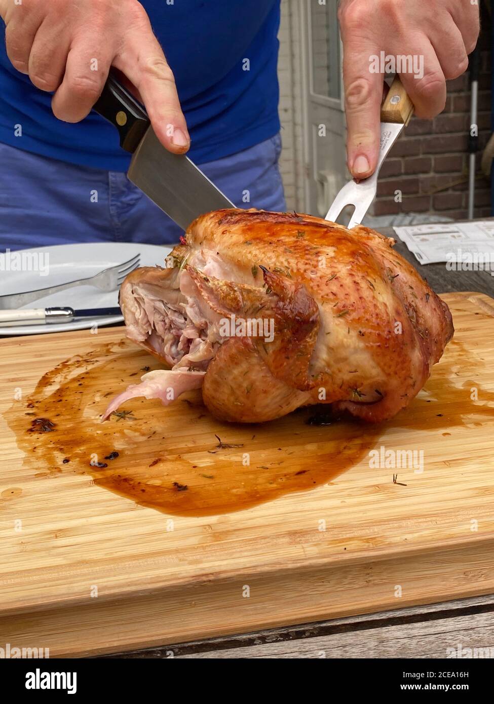 Homme coupant du poulet rôti sur une table à l'extérieur Banque D'Images