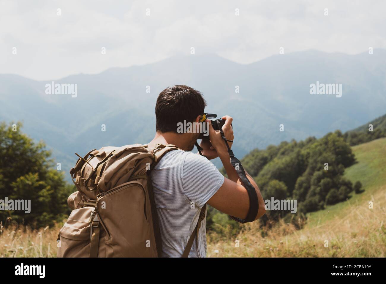 Vue arrière de l'homme avec sac à dos utilisation d'un appareil photo professionnel pour faire des photos de campagne pittoresque en Bulgarie, Balkans Banque D'Images