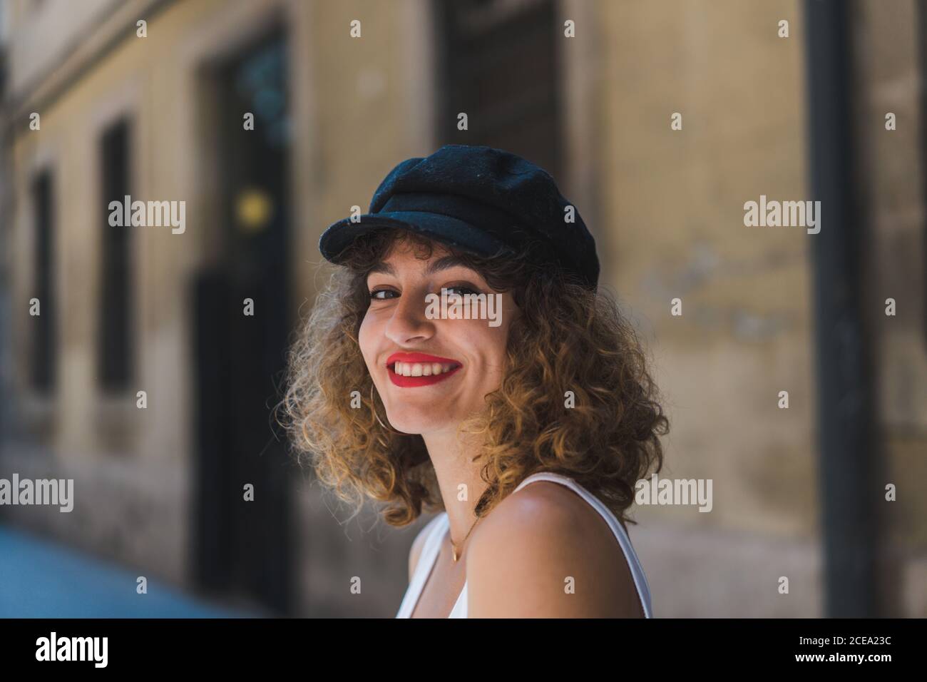 Jolie femme bouclés portant une casquette noire avec un short et un  débardeur regardant l'appareil photo dans la rue Photo Stock - Alamy