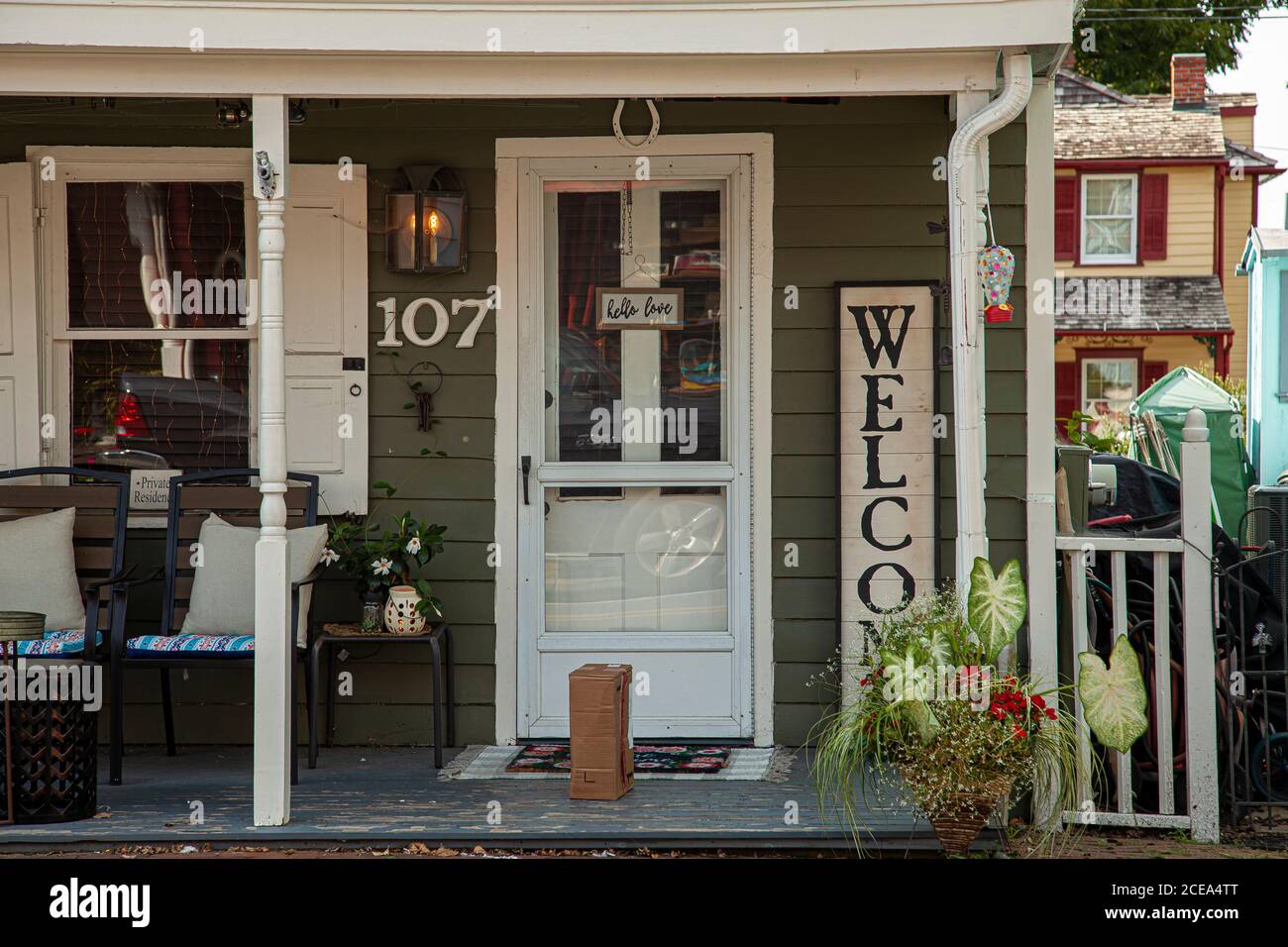 Chesapeake City, MD 08/25/2020: Porche avant d'une maison traditionnelle du XIXe siècle avec porte en bois blanc. Porte avec une breloque en forme de fer à cheval. Un Banque D'Images