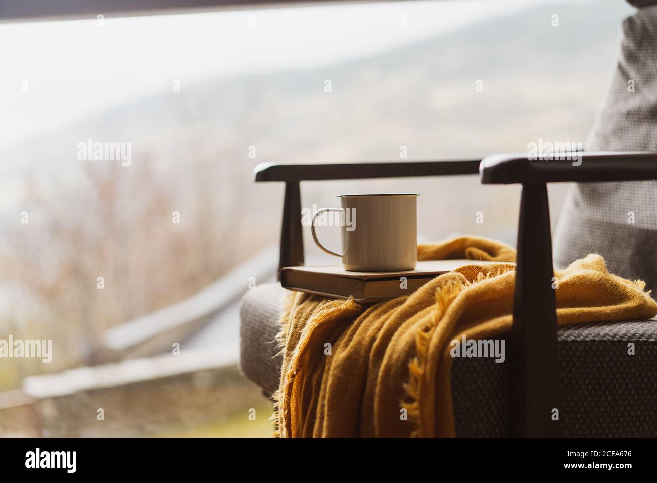 Une tasse de boisson chaude aromatique et un bon livre fauteuil confortable dans une grande fenêtre dans une chambre confortable Banque D'Images