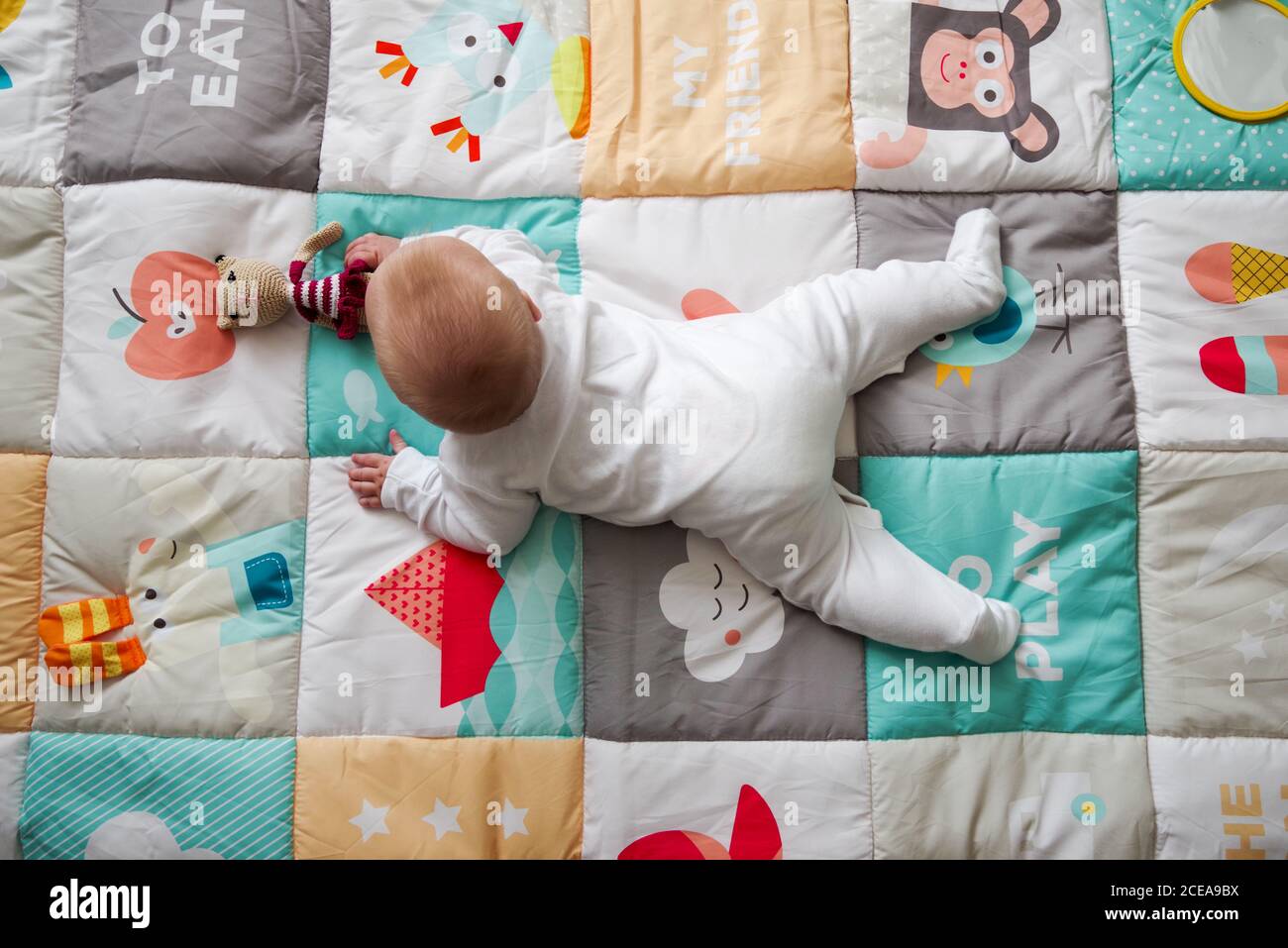 bébé de 5 mois allongé sur un tapis de jeu, arrivant à la recherche d'un jouet Banque D'Images
