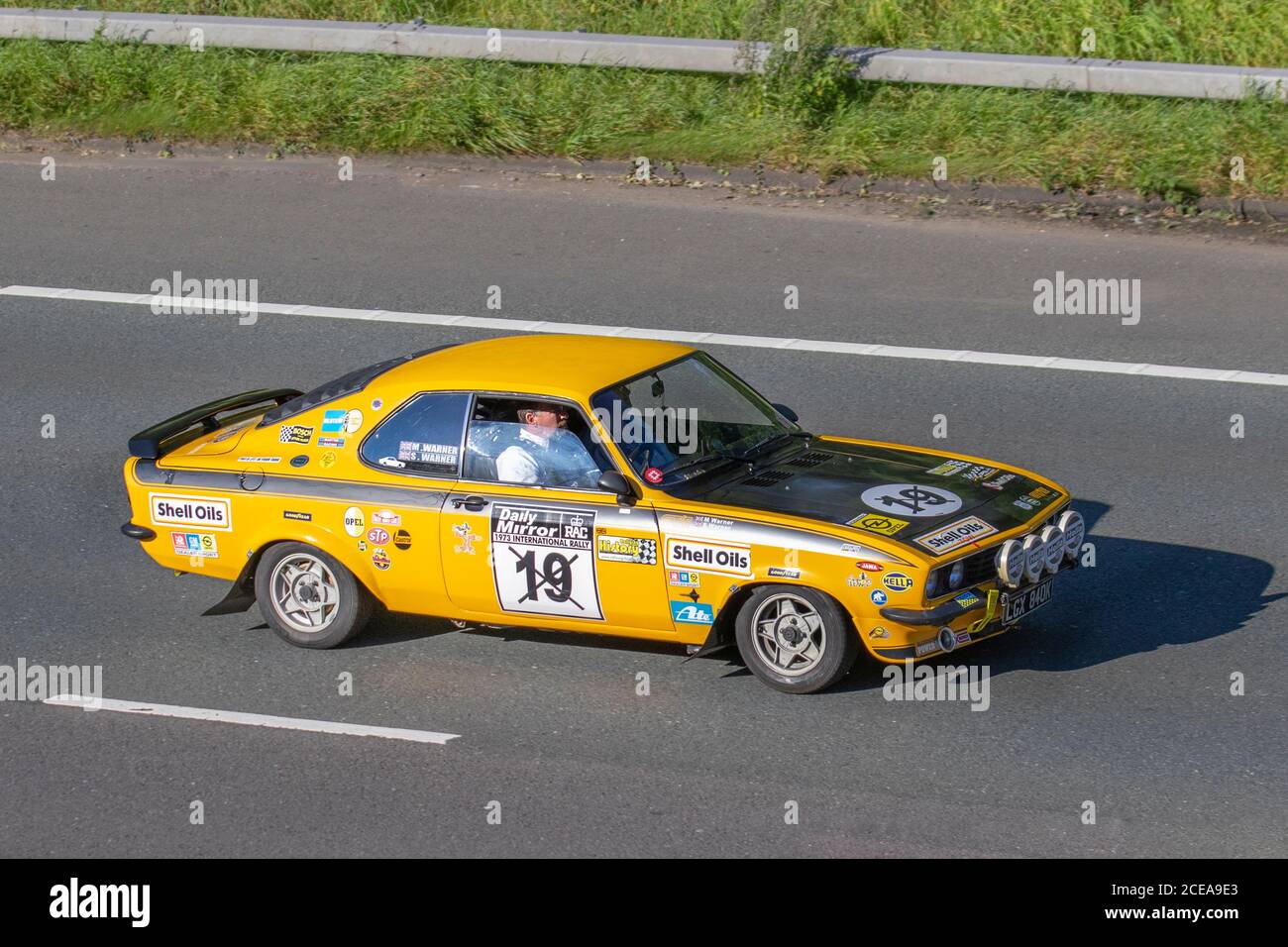 1972 70s jaune Opel Manta Motorsport No.19 voiture de course sponsorisée avec des décalques de sport automobile; véhicules mobiles de circulation automobile, voitures conduisant des véhicules sur les routes britanniques, moteurs, conduite sur le réseau autoroutier M6. Banque D'Images