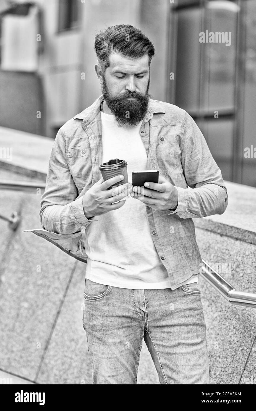 Café en pause. Homme barbu tient la tasse à emporter et smartphone. Pause café. La vie moderne. Communication avec le smartphone. Faites une pause. Son temps de pause, filtre vintage. Banque D'Images
