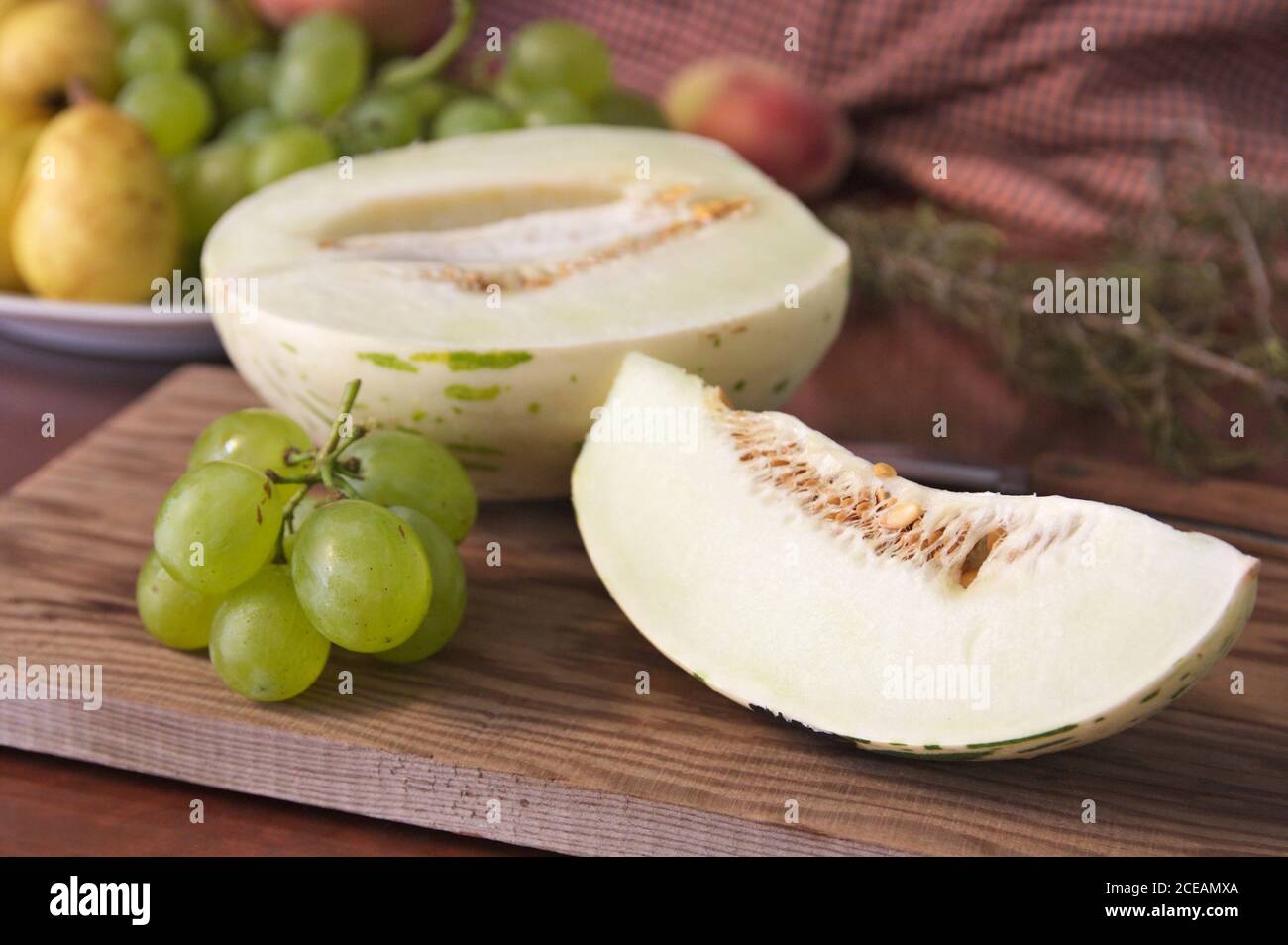 Encore la vie de fruit où vous pouvez voir une tranche De melon du type Matisse à côté d'un peu de vert raisins sur une table en bois Banque D'Images