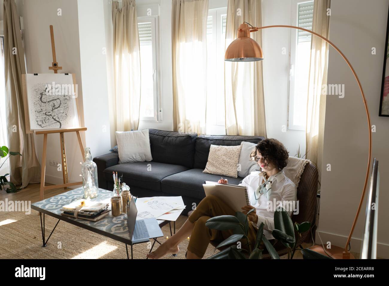 Femme écrit sur papier sur le canapé dans la chambre Banque D'Images