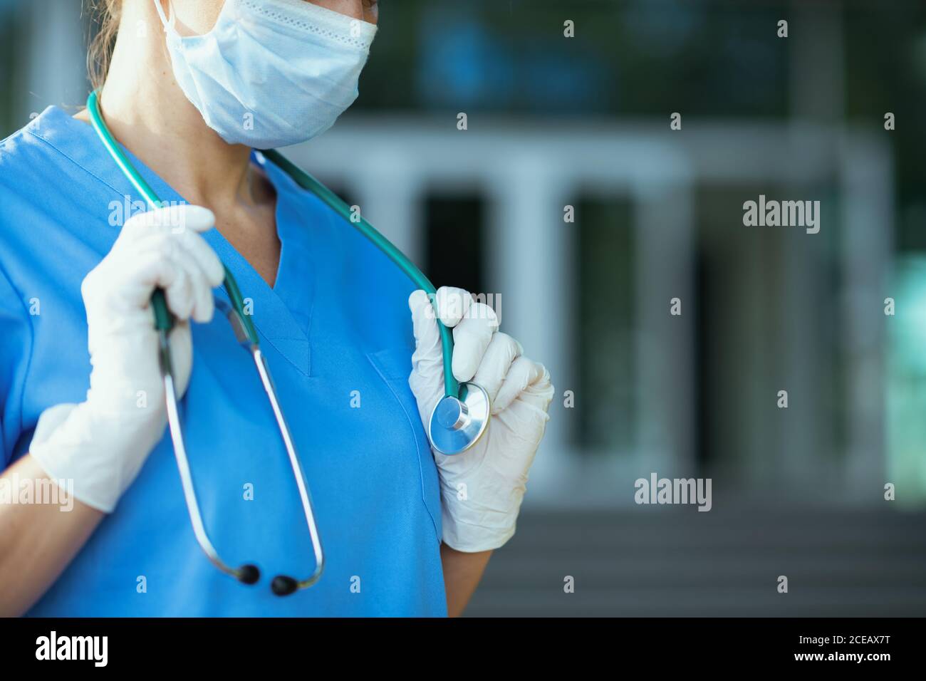 pandémie de coronavirus. Gros plan sur la femme médecin en uniforme avec stéthoscope et masque médical à l'extérieur près de la clinique. Banque D'Images