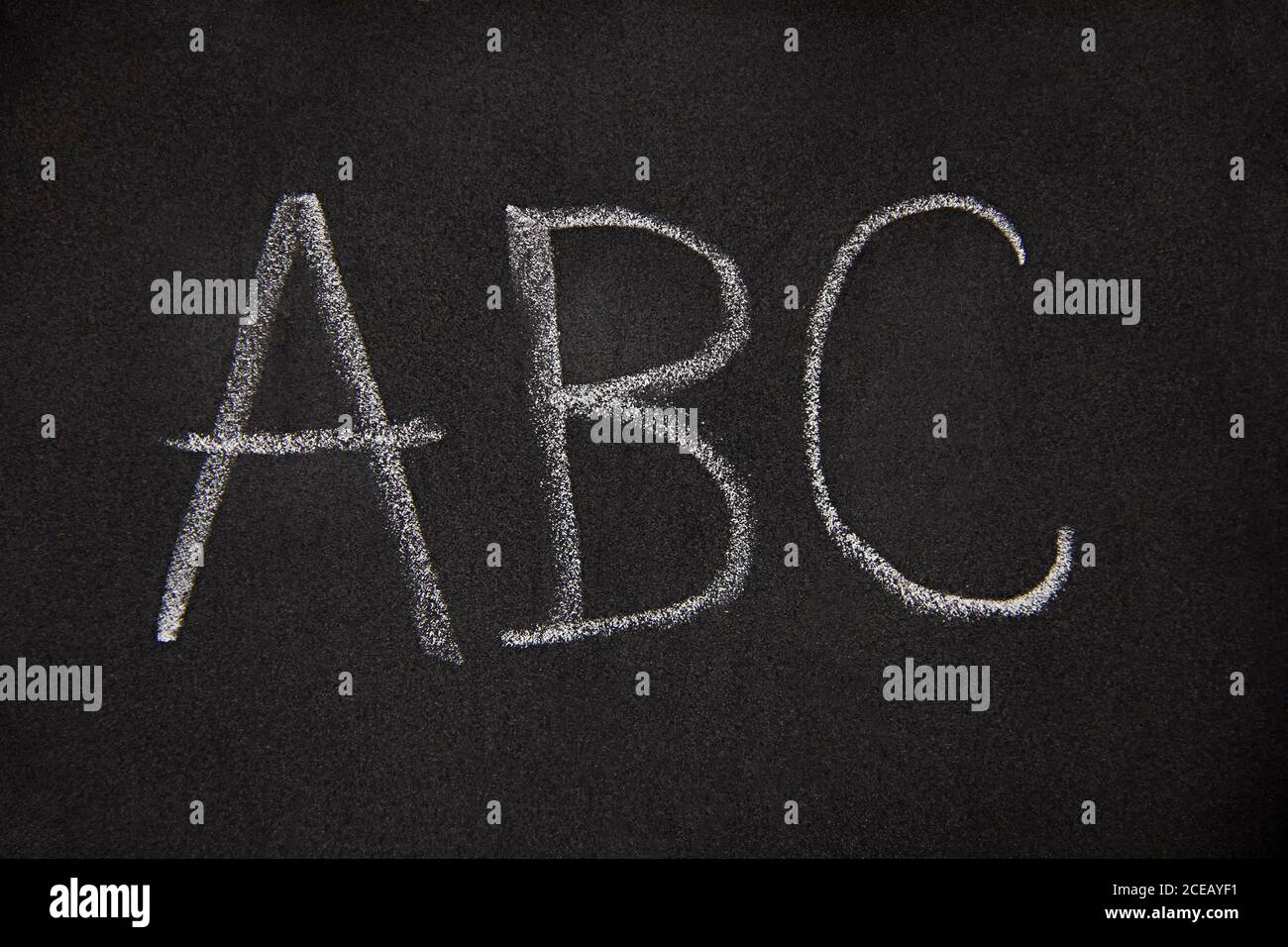 Les lettres A, B, C sont isolées en noir, gros plan des premières lettres de l'alphabet anglais écrites sur un tableau noir avec un morceau de craie Banque D'Images