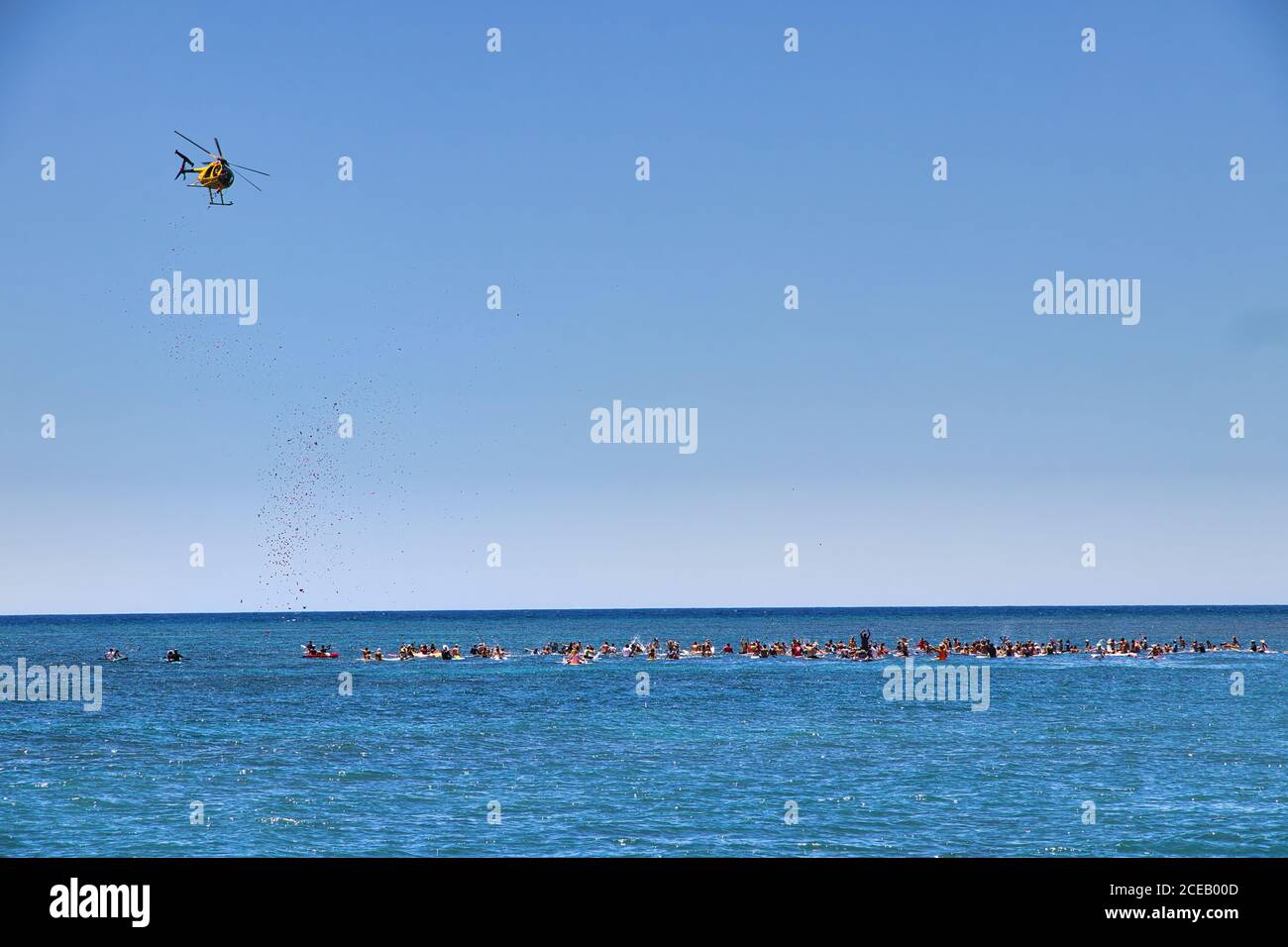 Un hélicoptère larguer des fleurs sur des surfeurs éloignés lors d'une cérémonie de célébration de la vie. Banque D'Images