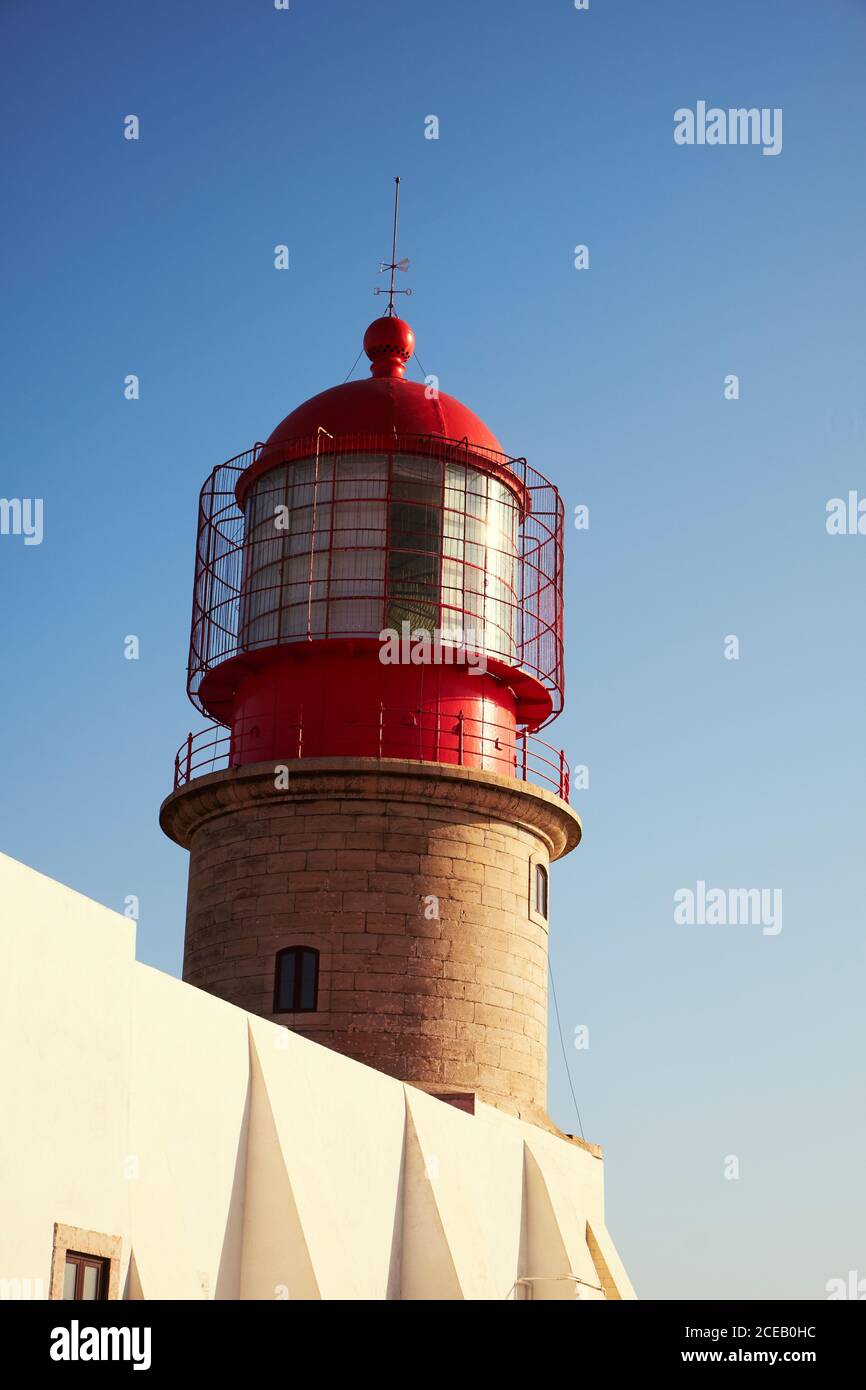 Peint en haut rouge du phare et en bas de briques sur un bâtiment blanc sur fond bleu clair Banque D'Images