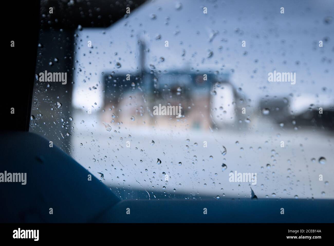 Prise de vue à travers le pare-brise avec les essuie-glaces en mouvement par temps de pluie conduite en ville Banque D'Images