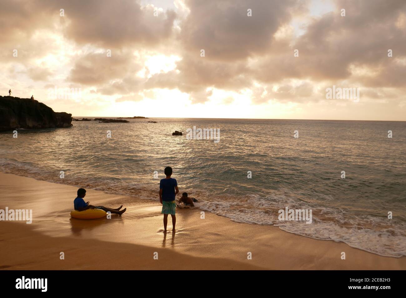Enfants jouant, Sunset Waimea Bay, North Shore, Oahu, Hawaï Banque D'Images