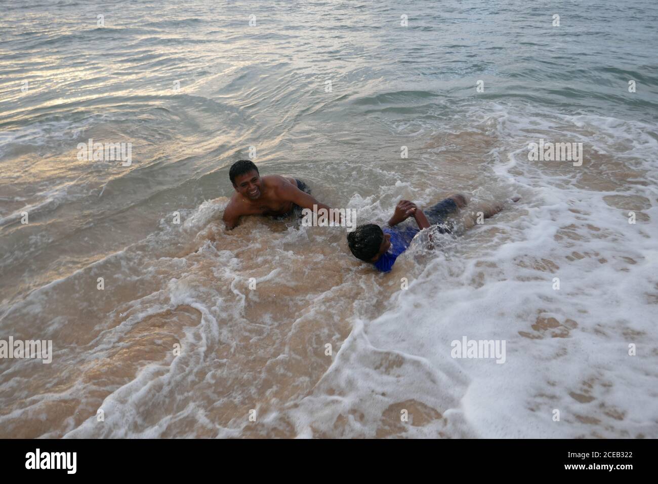 Enfants jouant, Sunset Waimea Bay, North Shore, Oahu, Hawaï Banque D'Images