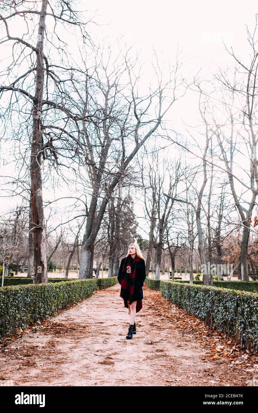 Jeune femme en robe rouge marchant dans le parc Banque D'Images
