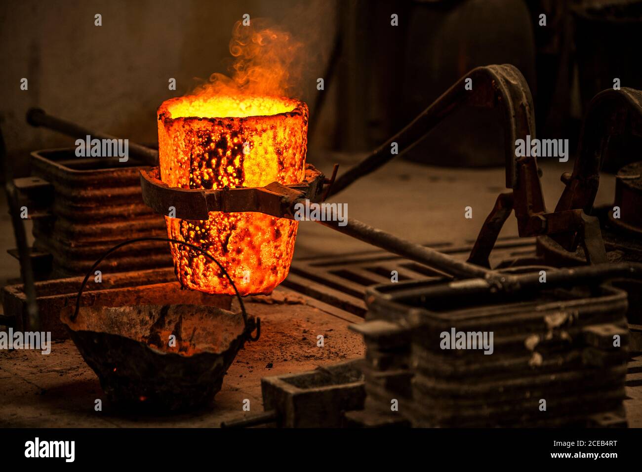 Vue rognée de l'homme dans les vêtements de travail debout et empêchant fours à charbon avec feu Banque D'Images